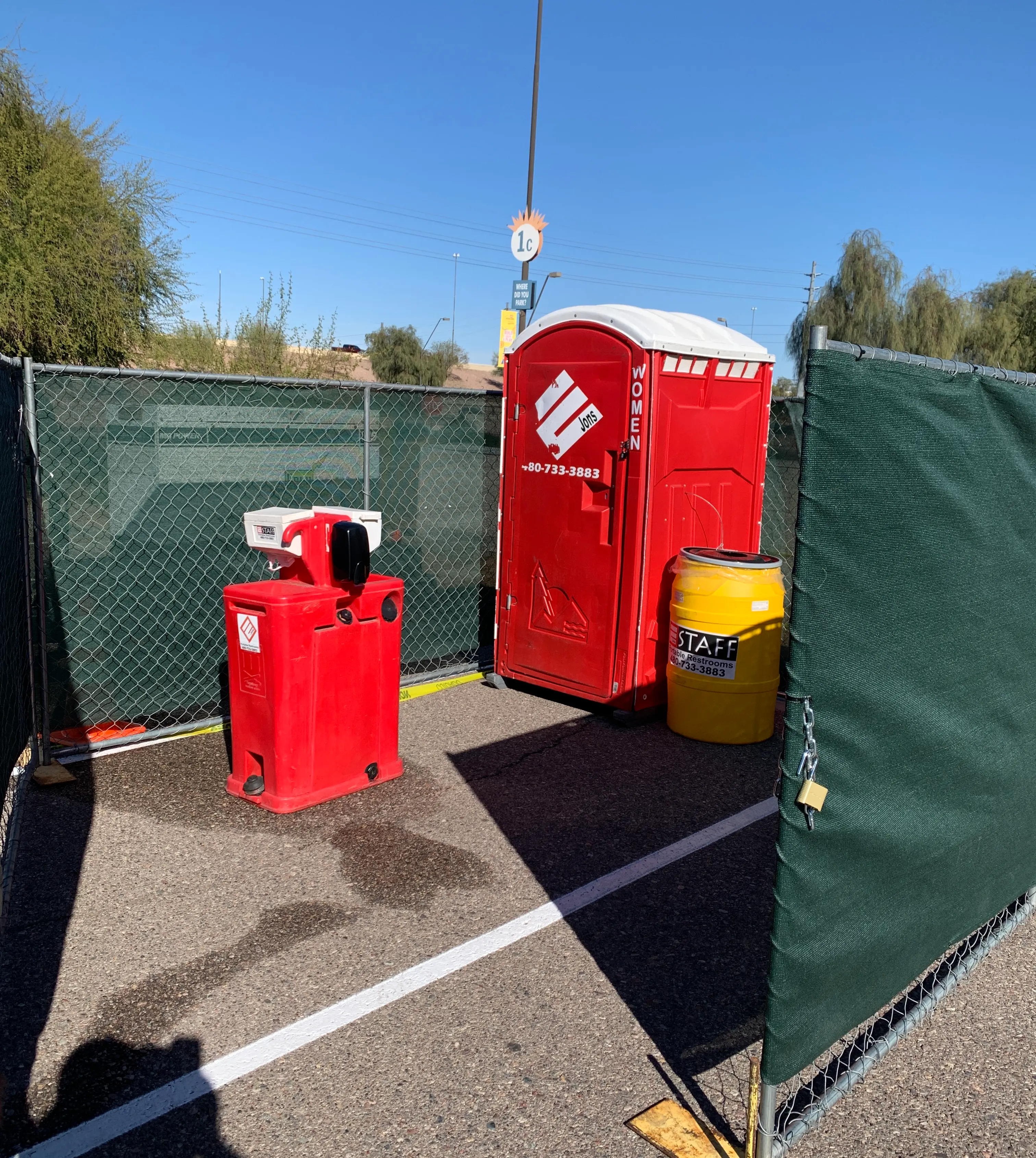 A portable restroom, hand-washing station, and trash can